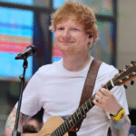 Ed Sheeran performing live with a smile during the launch of his new single “Azizam,” capturing the lovestruck jitters of his romantic pop song