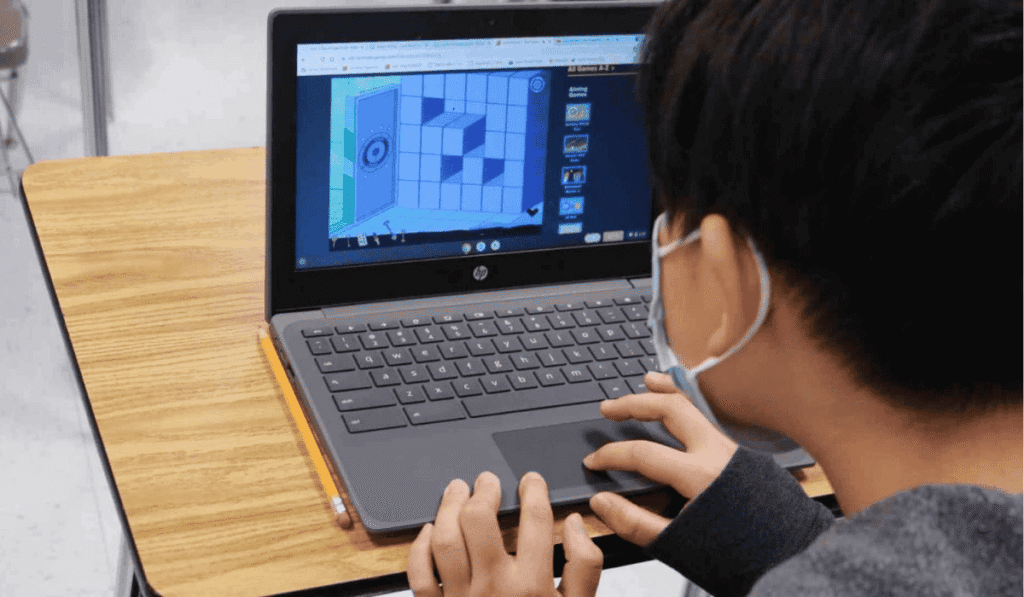 Real student playing an unblocked Classroom 15x game on a school Chromebook at a classroom desk, wearing a mask and focused on a puzzle-style game screen.